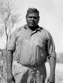 Albert Namatjira standing with country in the background.