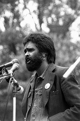 Close-up of Gary Foley speaking in front of two microphones.