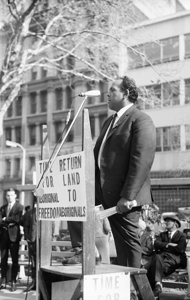 The placard refers to land. The speaker is Aboriginal trade unionist, Ray Peckham.